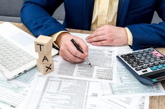 Brazilian tax and accounting documents with a calculator and laptop on an office desk.